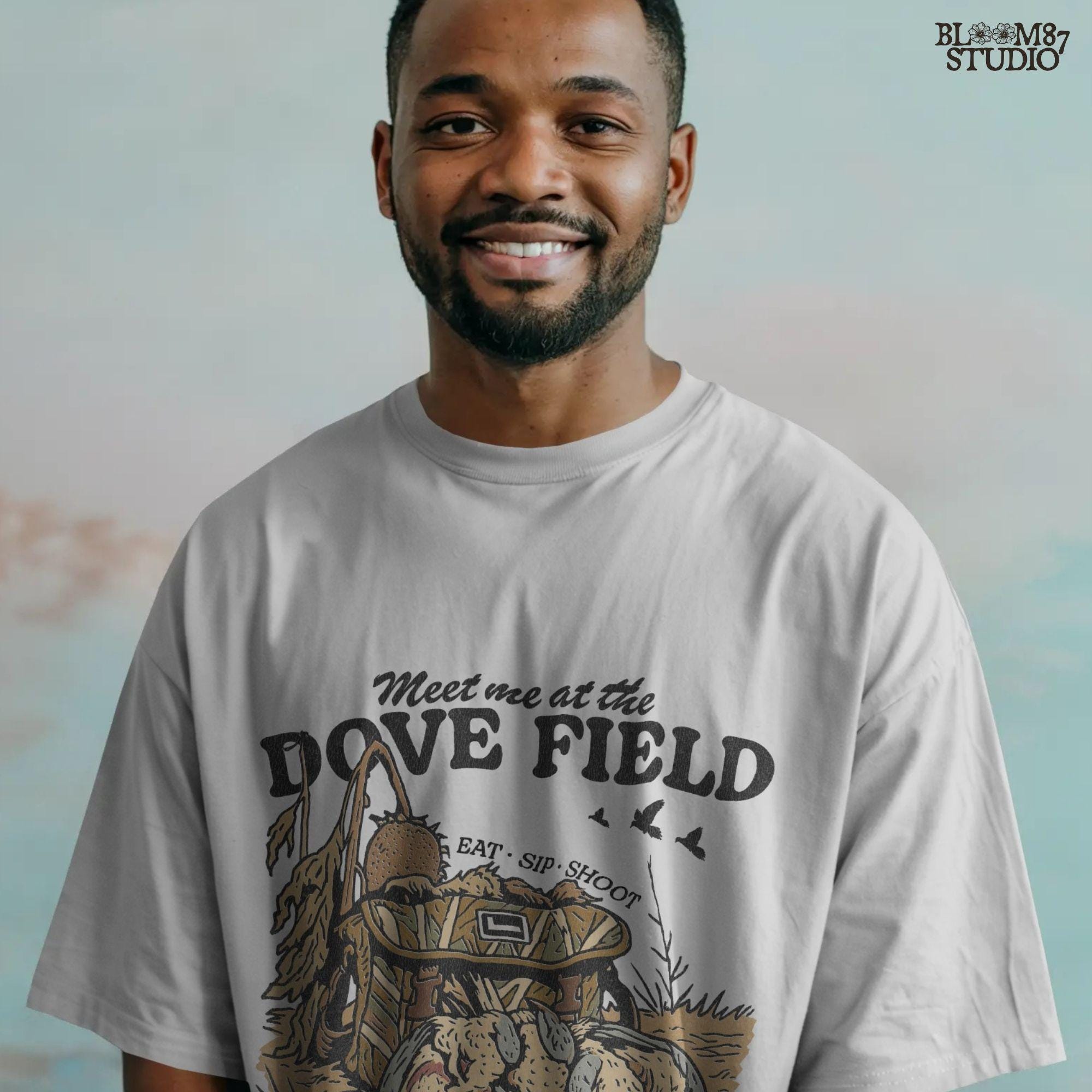Camo hunting bag in a cornfield surrounded by harvested mourning doves with the phrase “Meet Me at the Dove Field” in vintage lettering.