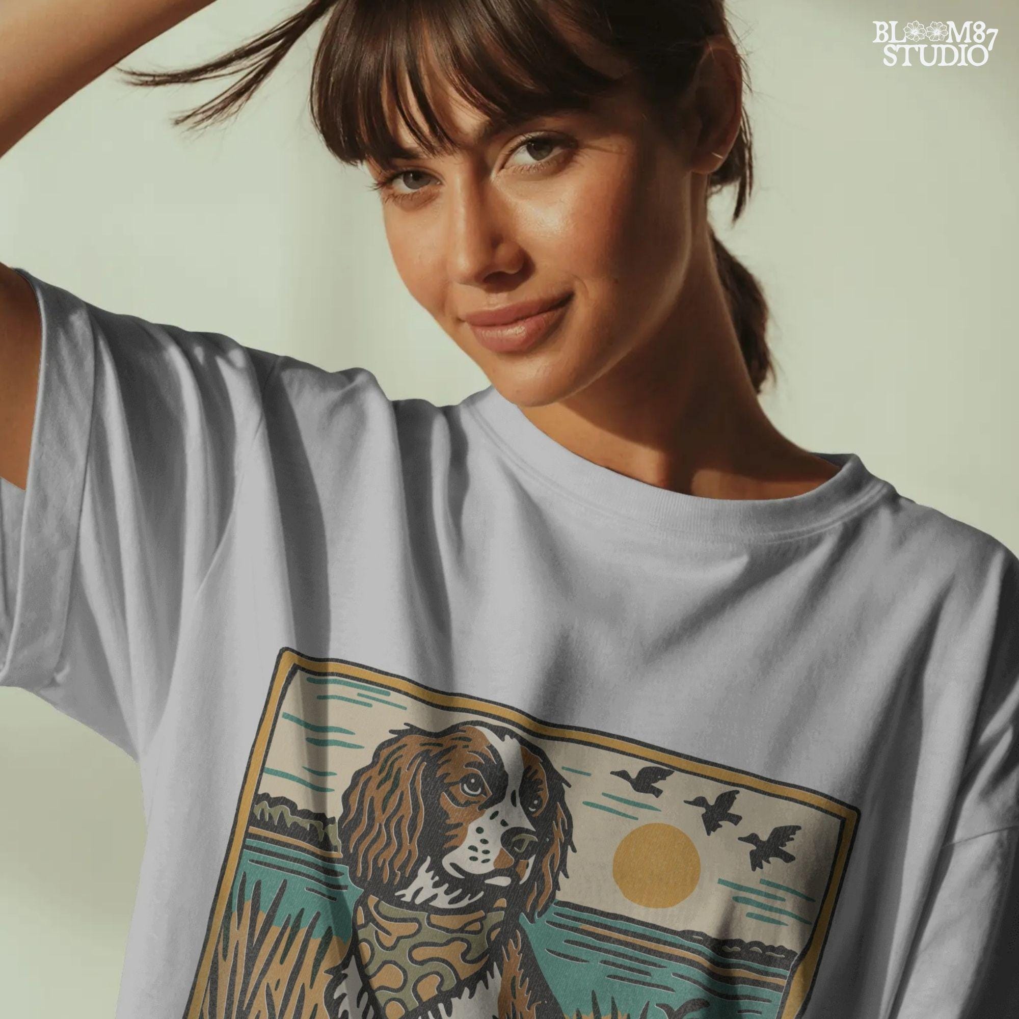 Illustration of a spaniel dog in a camouflage bandana sitting near a lake with sunset and ducks flying overhead; rustic southern sublimation PNG for apparel.