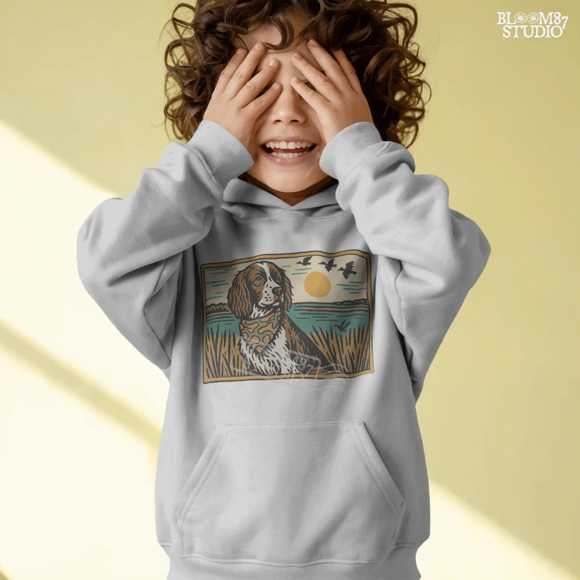 Illustration of a spaniel dog in a camouflage bandana sitting near a lake with sunset and ducks flying overhead; rustic southern sublimation PNG for apparel.