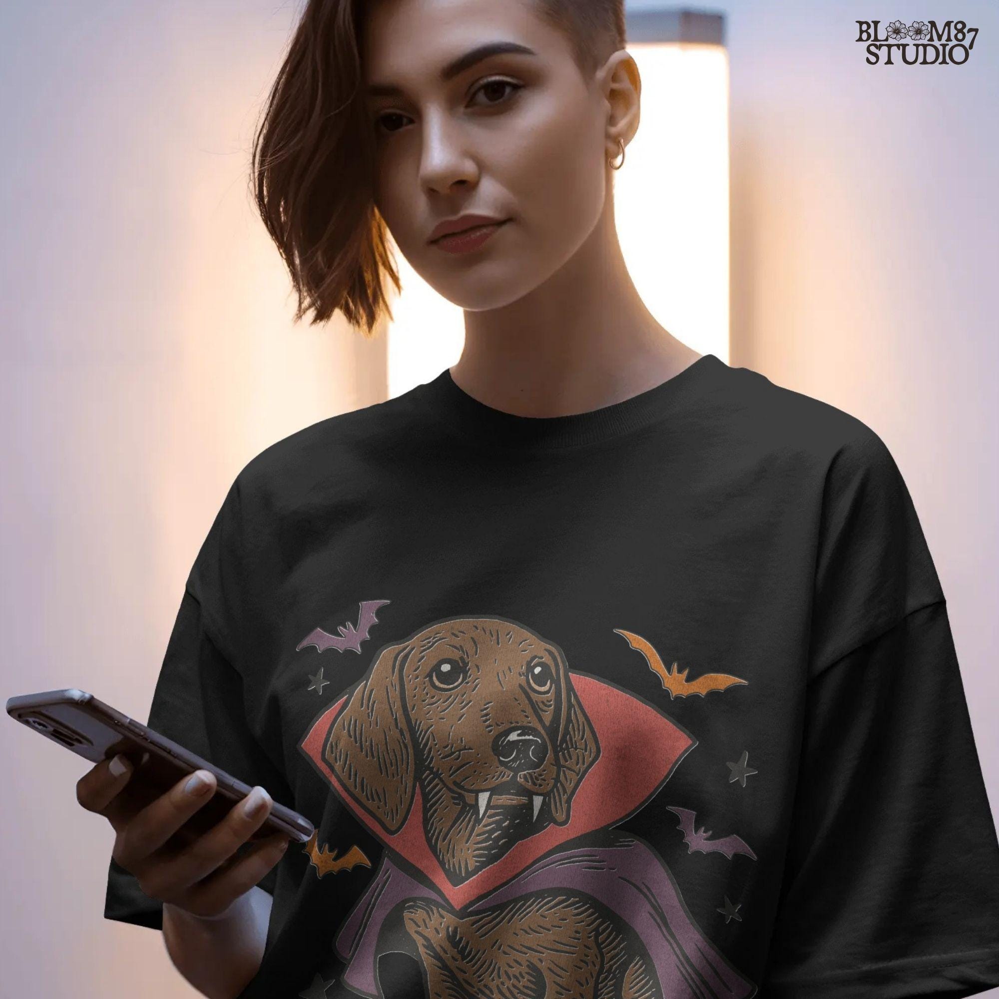 Cute dachshund dressed as a Halloween vampire with red and purple cape, fangs, and surrounded by bats on transparent background.