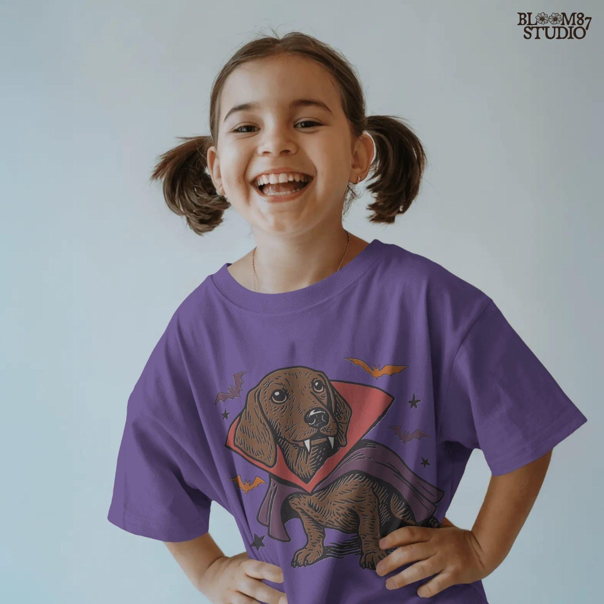 Cute dachshund dressed as a Halloween vampire with red and purple cape, fangs, and surrounded by bats on transparent background.