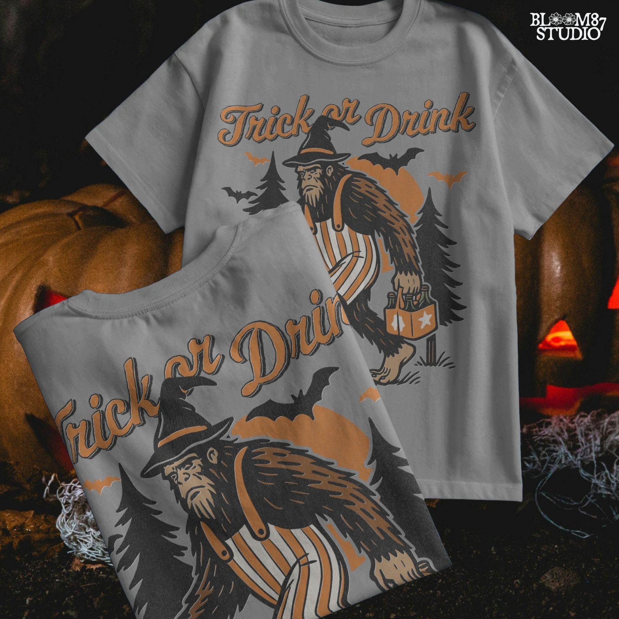 Funny Halloween bigfoot holding beer in witch hat and striped overalls, walking past pumpkins and trees with “Trick or Drink” text above.