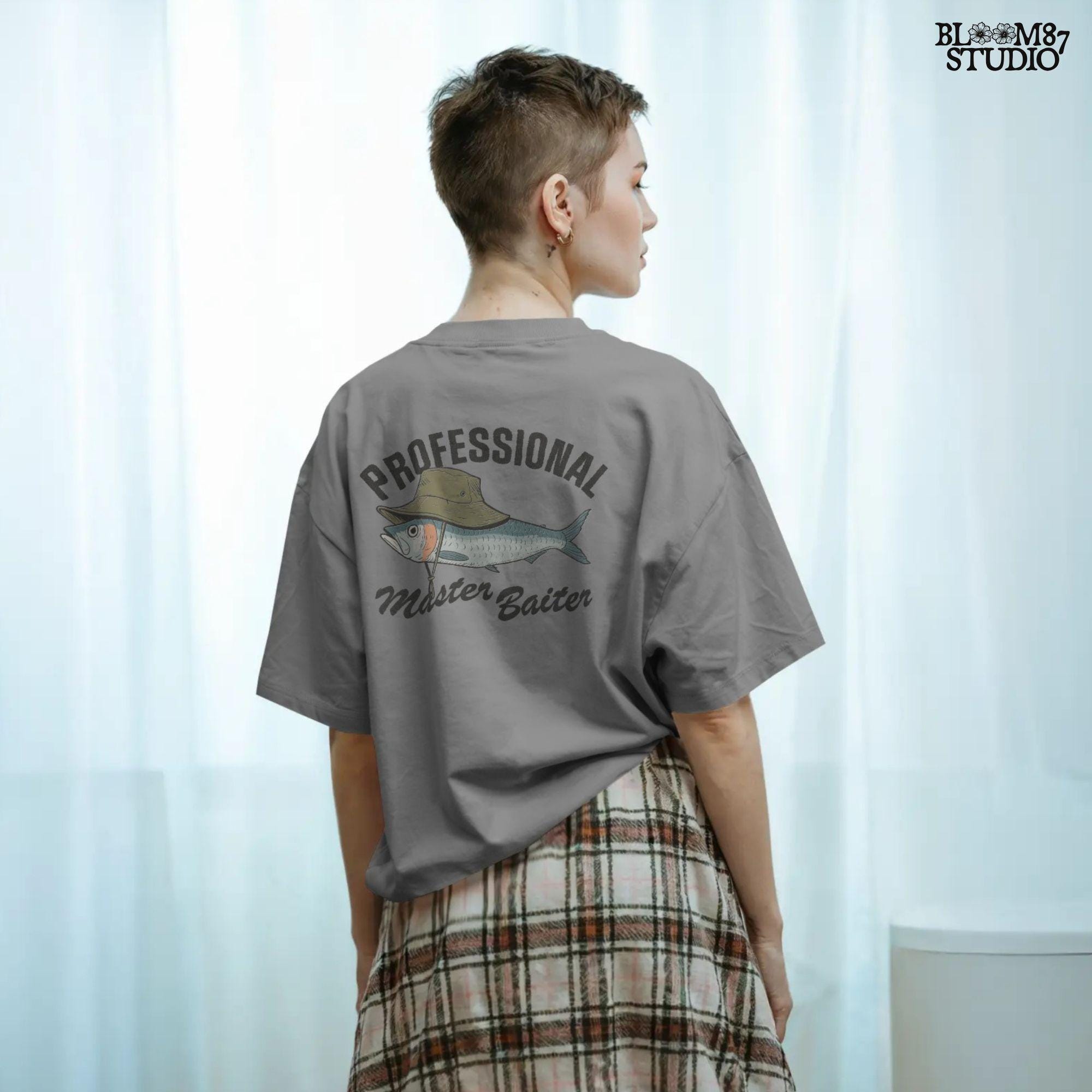 Funny fishing sublimation PNG with a fish wearing a green bucket hat and the words “Professional Master Baiter” in vintage bold font.