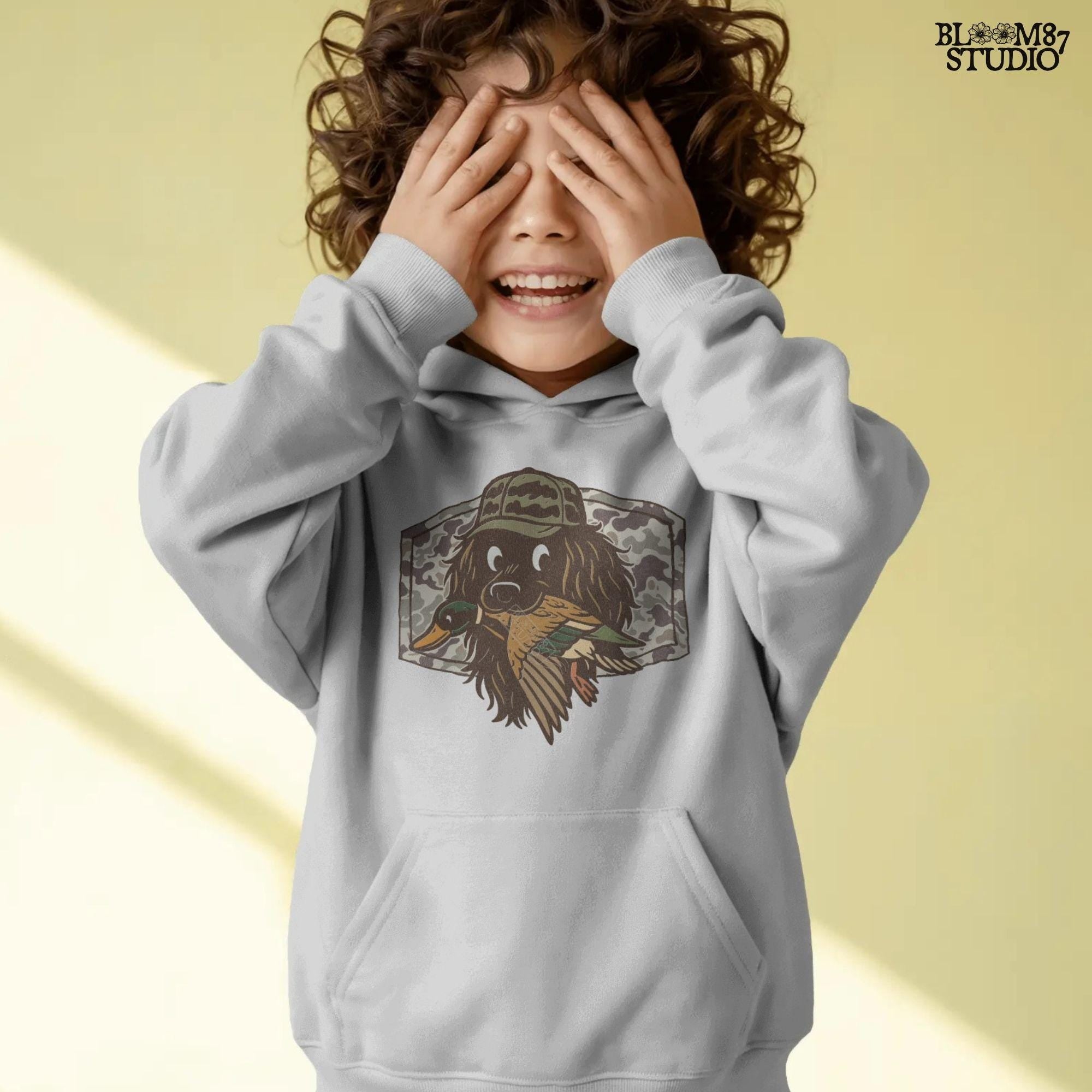 Cute cartoon hunting dog wearing camo hat holding a duck in its mouth with a camo background – sublimation PNG for boys or fall kids apparel design.