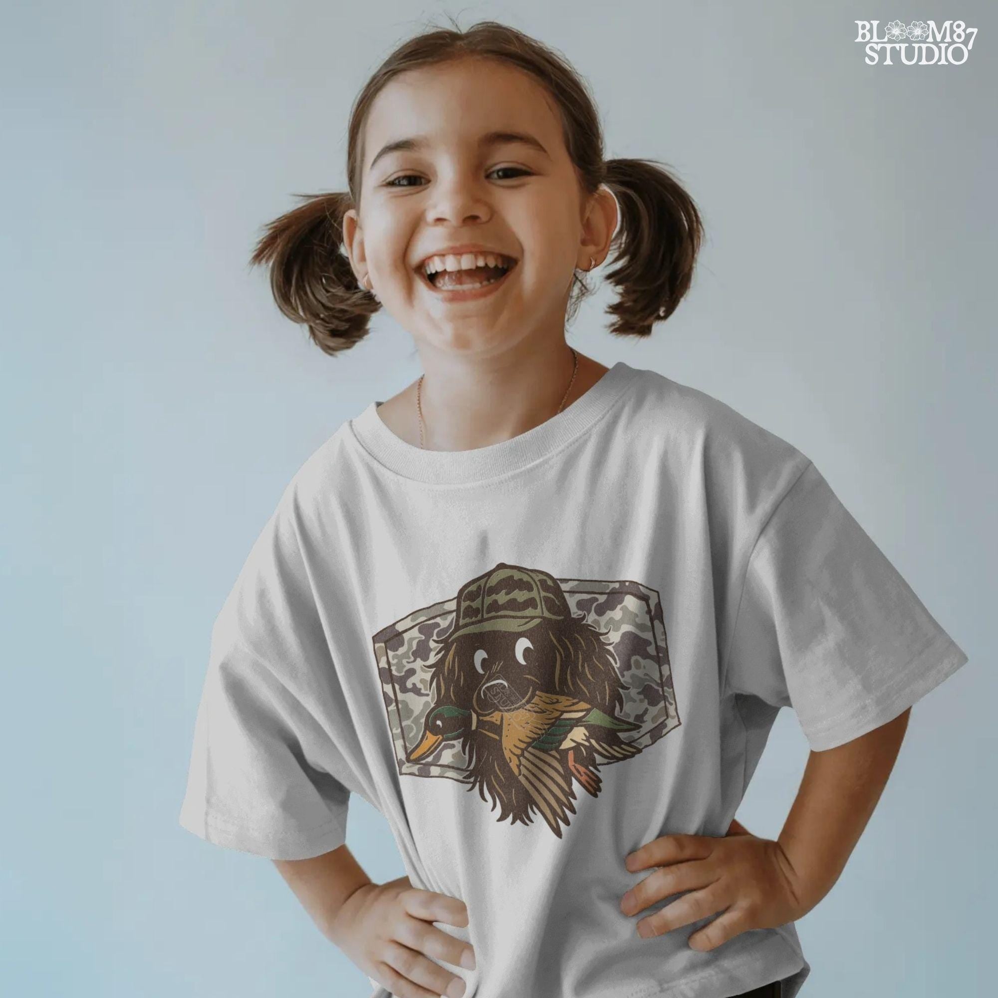 Cute cartoon hunting dog wearing camo hat holding a duck in its mouth with a camo background – sublimation PNG for boys or fall kids apparel design.