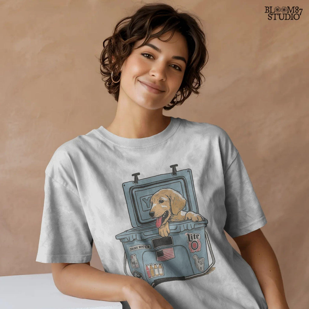 Illustration of a golden retriever puppy sitting inside a YETI cooler covered in stickers, designed for sublimation and lake life dog dad gifts.