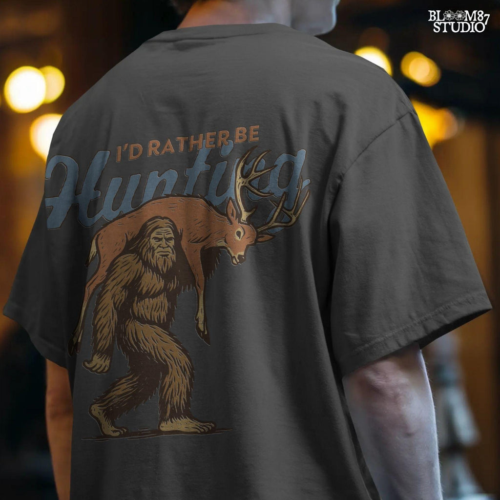 Illustration of Bigfoot carrying a deer on shoulders with text “I’d Rather Be Hunting,” designed for funny rustic sublimation projects