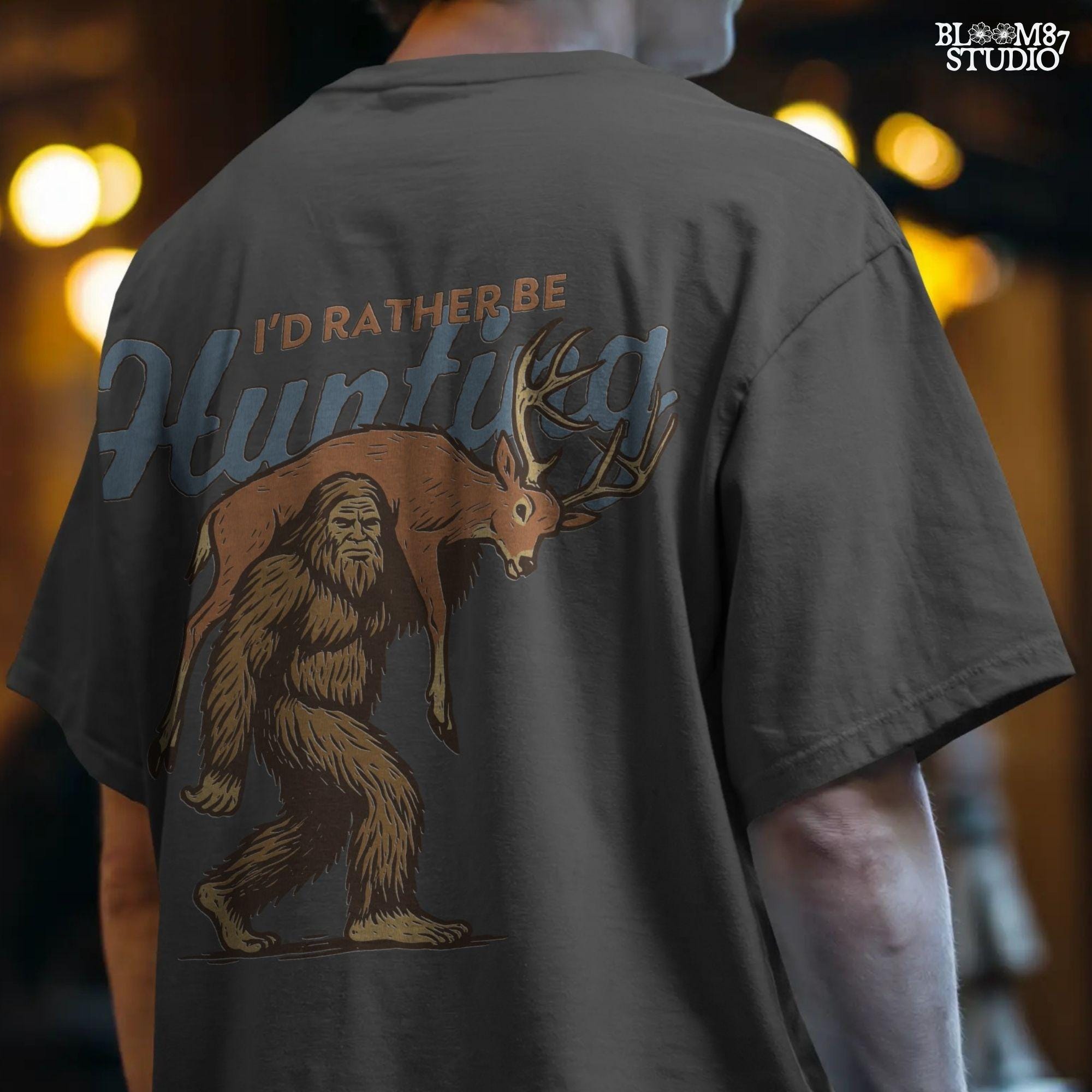 Illustration of Bigfoot carrying a deer on shoulders with text “I’d Rather Be Hunting,” designed for funny rustic sublimation projects
