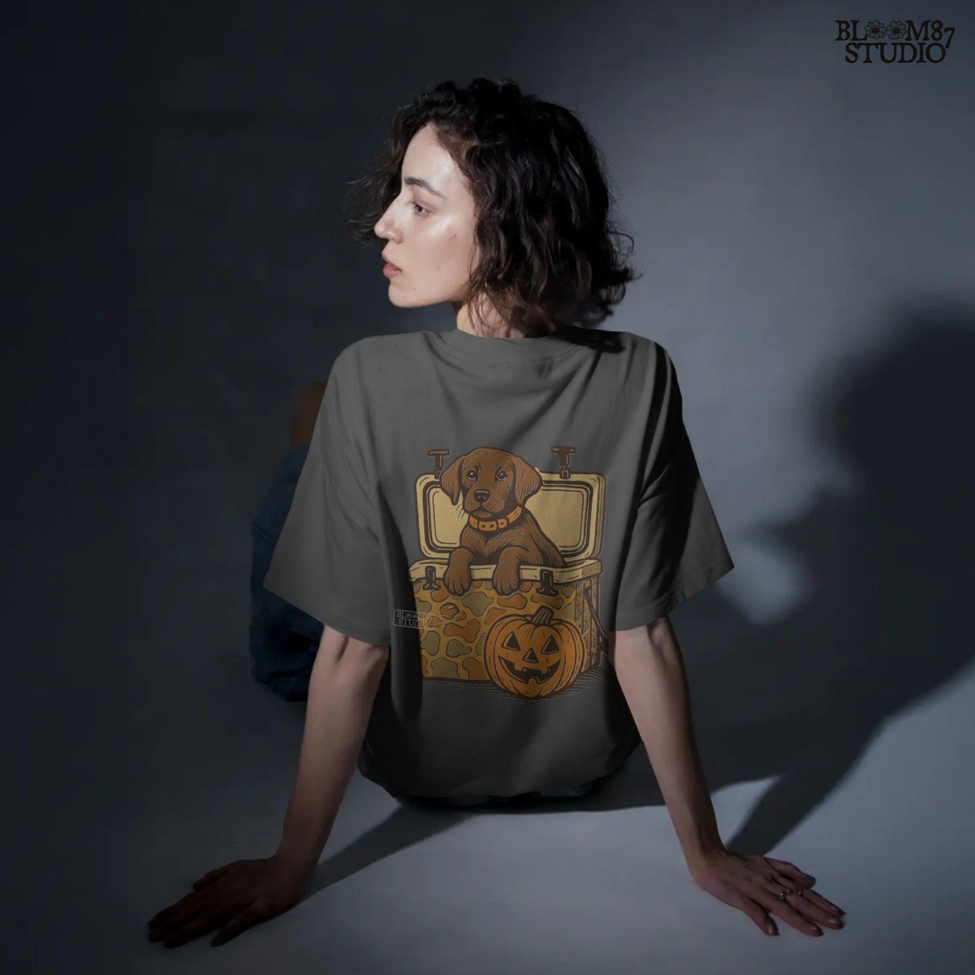 Cute brown hunting dog in a camo cooler next to a carved pumpkin, Halloween-themed sublimation PNG for fall shirts or seasonal crafts.