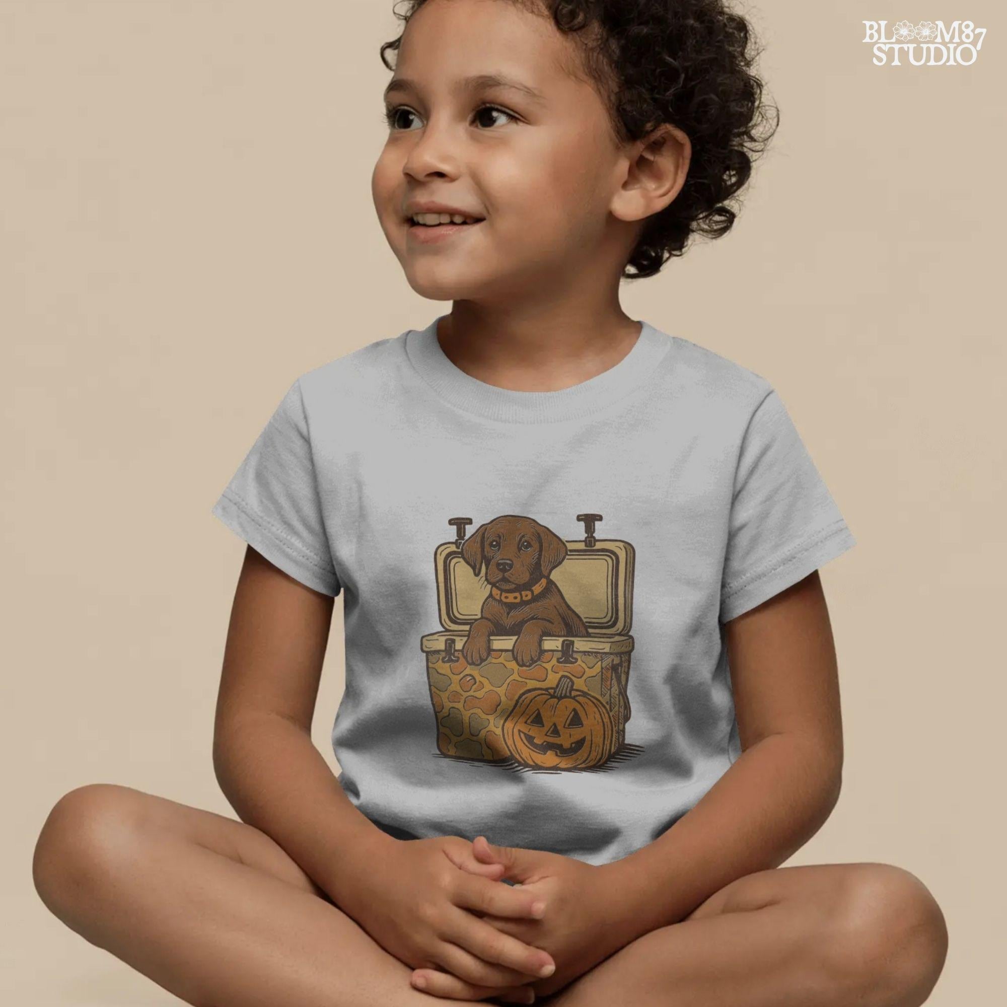 Cute brown hunting dog in a camo cooler next to a carved pumpkin, Halloween-themed sublimation PNG for fall shirts or seasonal crafts.