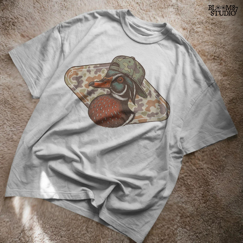 Illustration of a wood duck with a camouflage hat, placed over a brown woodland camo background, styled for fall hunting and Thanksgiving crafts.