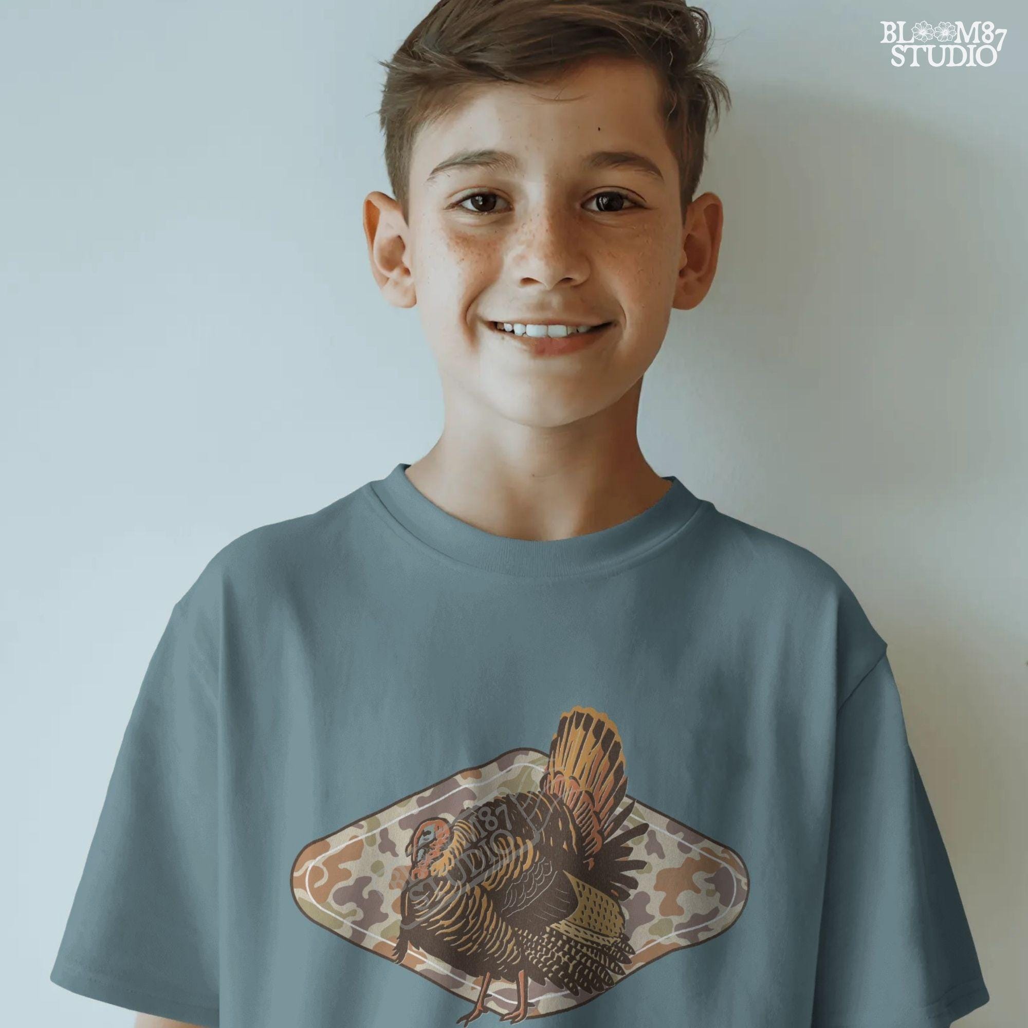 Illustration of a wild turkey with full plumage standing over a tan woodland camouflage background, ideal for fall or Thanksgiving sublimation designs.