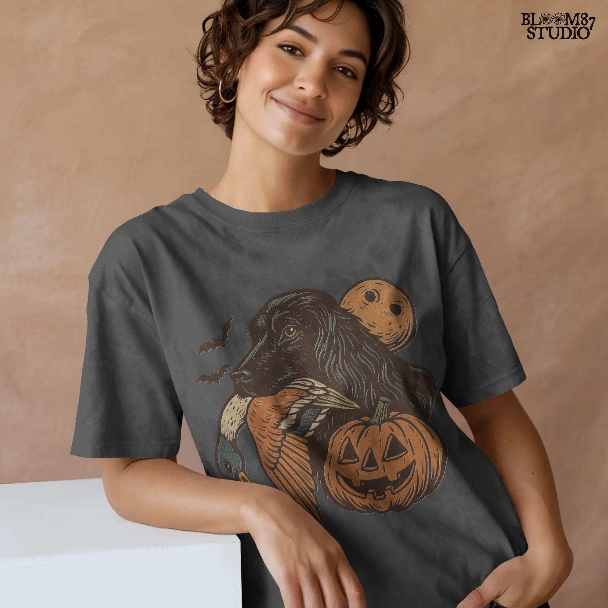 Halloween PNG of a black hunting dog holding a duck with jack-o’-lanterns, bats, and a full moon, rustic sublimation for fall crafts