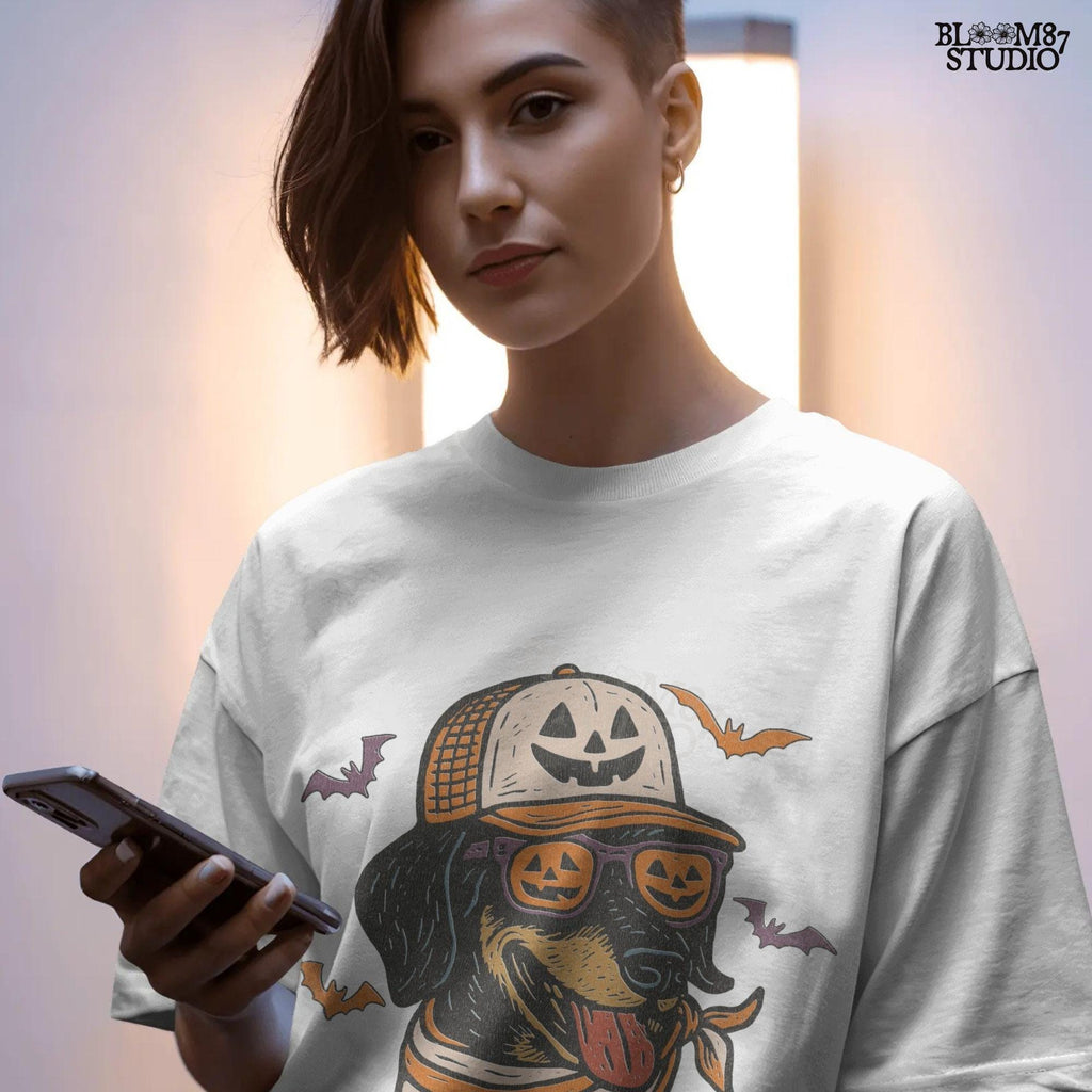 Halloween dachshund wearing pumpkin sunglasses, jack-o’-lantern hat, and orange bandana with flying bats, sublimation PNG design