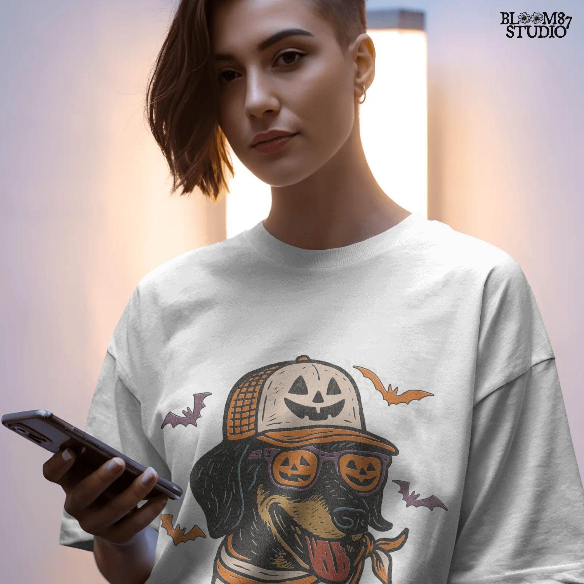 Halloween dachshund wearing pumpkin sunglasses, jack-o’-lantern hat, and orange bandana with flying bats, sublimation PNG design