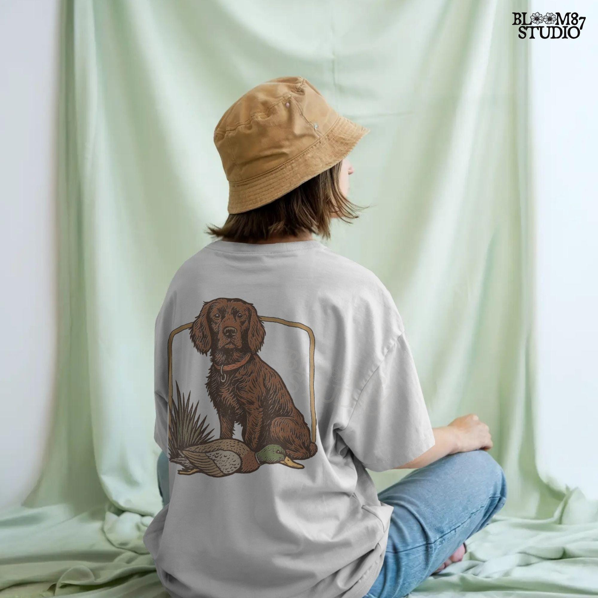 Vintage-style PNG of a Boykin Spaniel dog sitting with a harvested mallard duck, perfect for fall hunting sublimation and Southern dog lovers