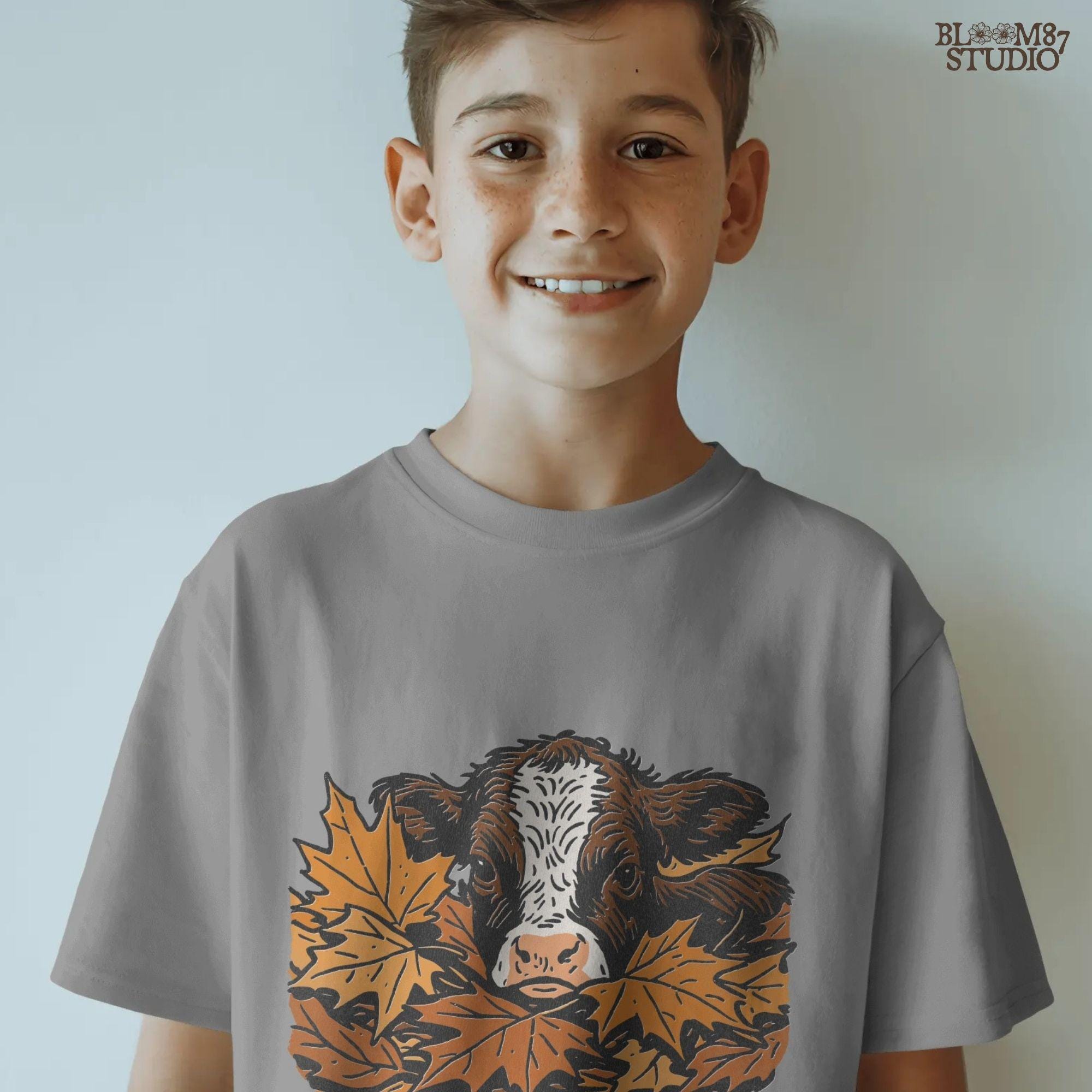 Cute brown and white highland calf resting in a pile of orange and brown fall maple leaves, perfect for autumn sublimation projects