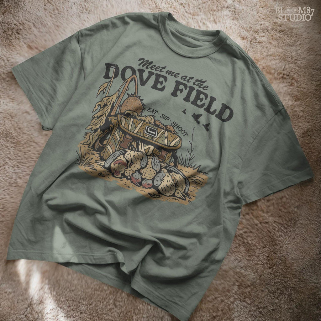 Camo hunting bag in a cornfield surrounded by harvested mourning doves with the phrase “Meet Me at the Dove Field” in vintage lettering.
