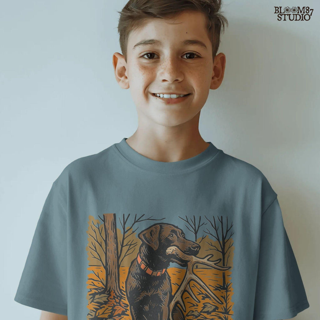 Illustration of a black Labrador dog sitting in autumn leaves holding a deer antler in its mouth, rustic hunting sublimation PNG design.