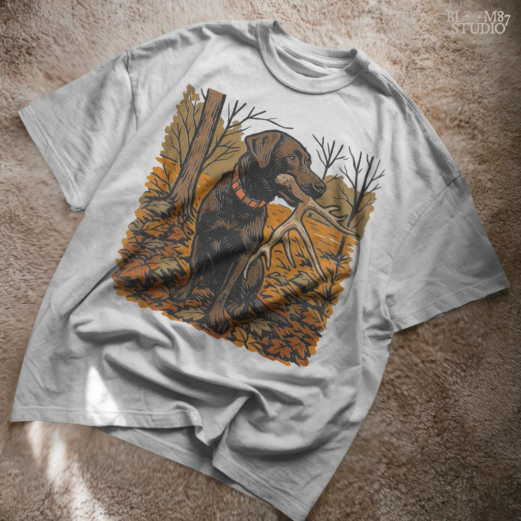 Illustration of a black Labrador dog sitting in autumn leaves holding a deer antler in its mouth, rustic hunting sublimation PNG design.