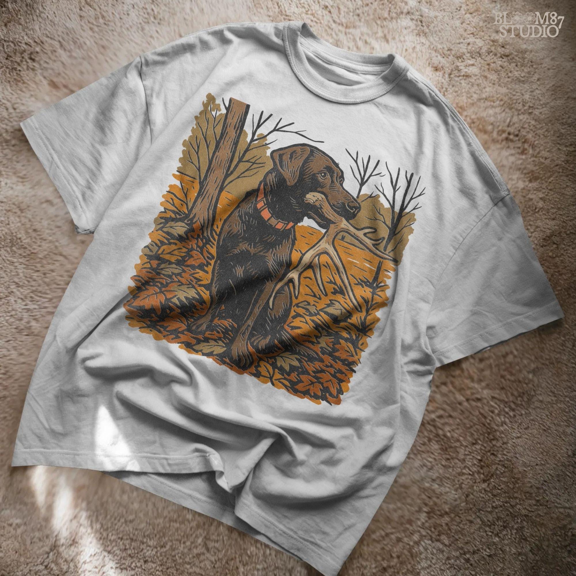 Illustration of a black Labrador dog sitting in autumn leaves holding a deer antler in its mouth, rustic hunting sublimation PNG design.