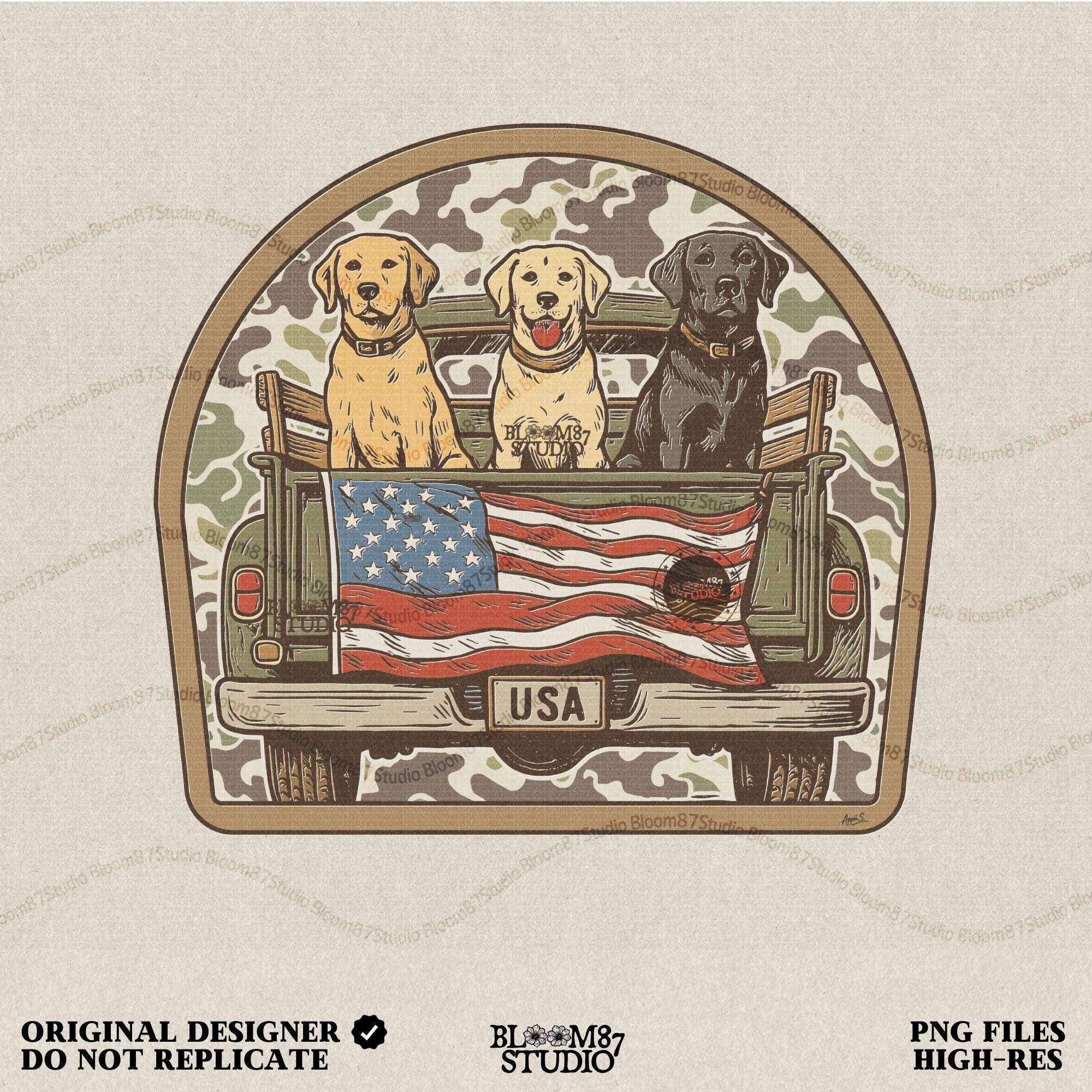 Three Labrador retrievers — yellow, chocolate, and black — sitting on the back of a green camouflage pickup truck with an American flag and the words “Local Boy” underneath.