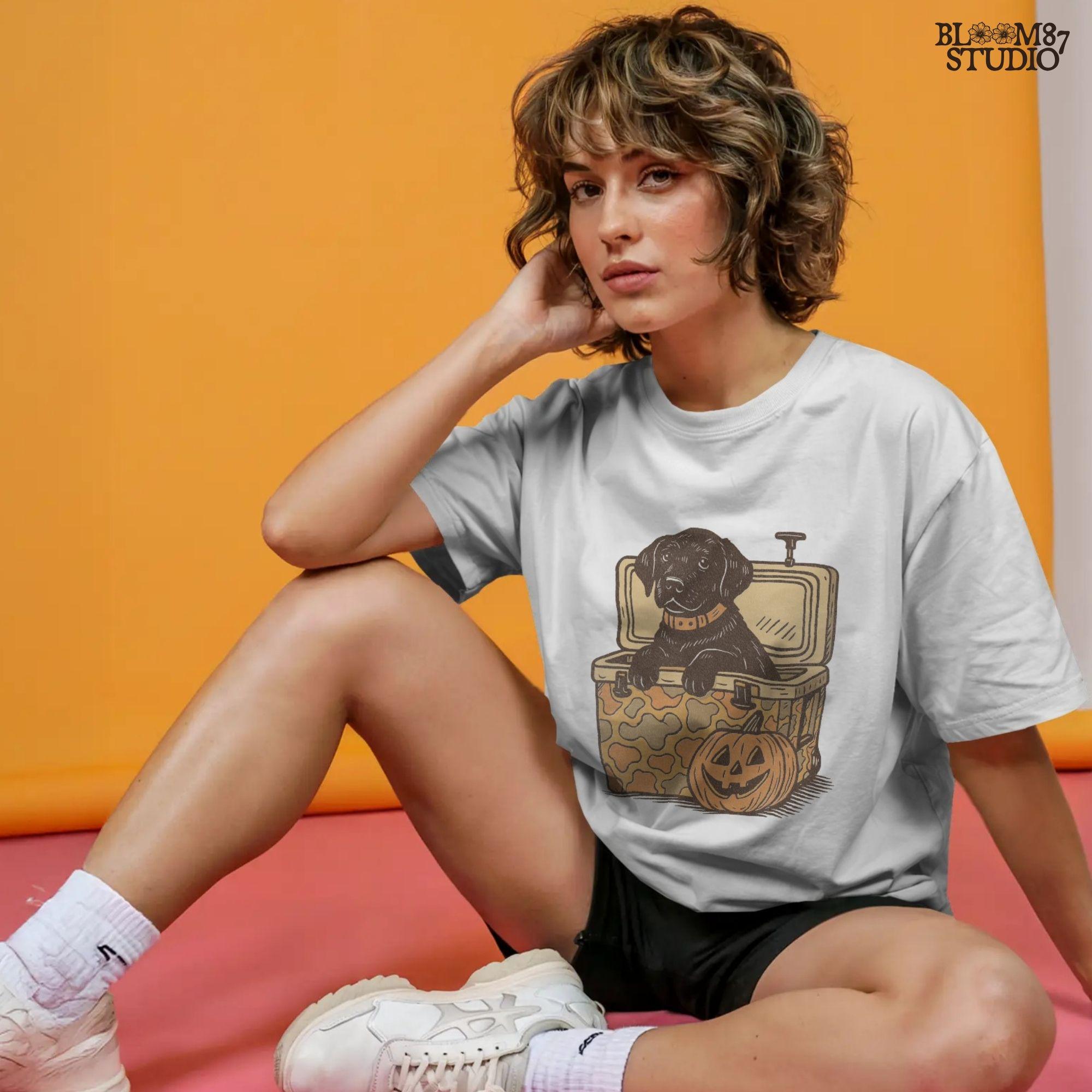 Black Labrador retriever sitting in a cooler with a pumpkin, Halloween sublimation PNG design for dog lovers, seasonal crafts, and apparel.