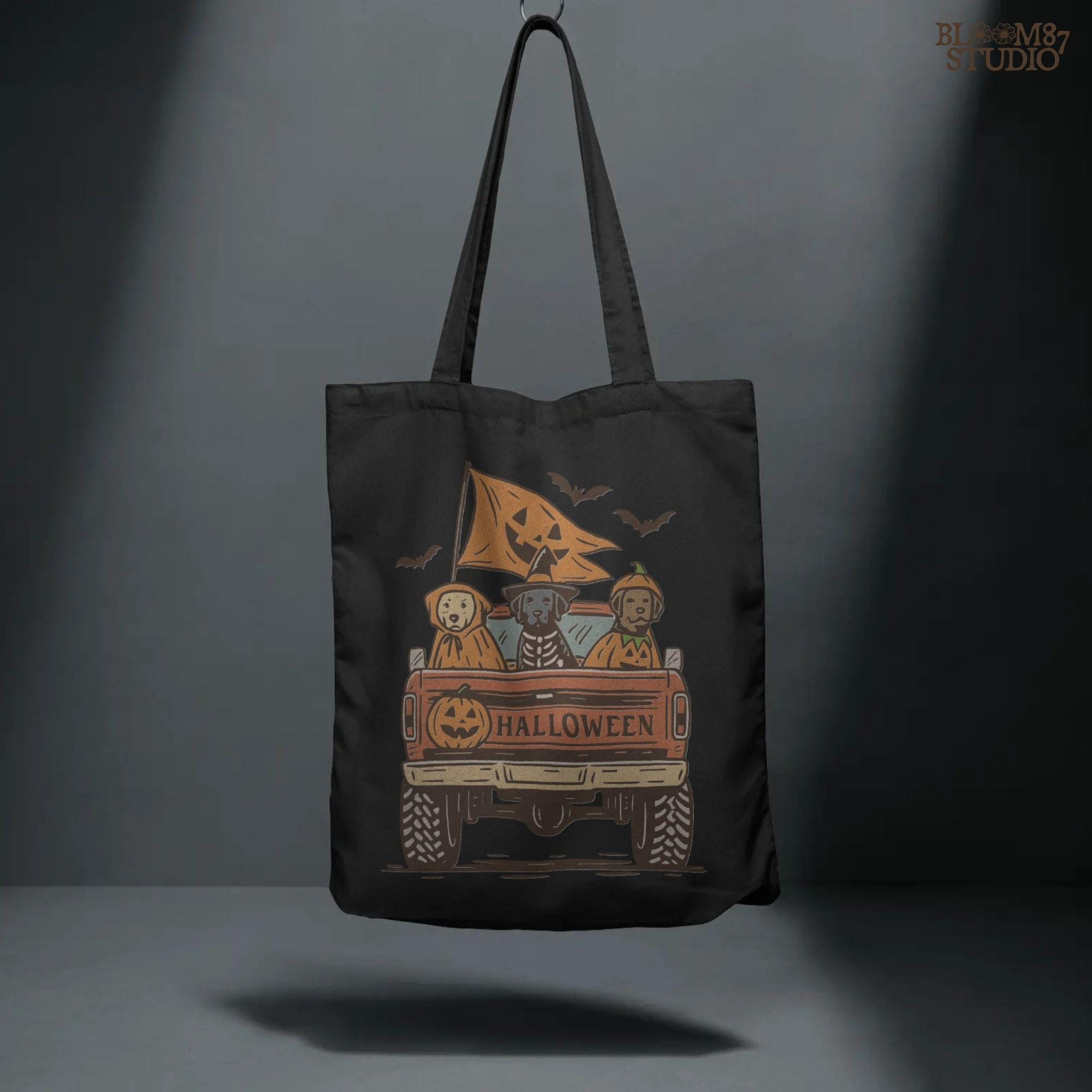 Halloween PNG of three dogs in Halloween costumes riding in a vintage truck with pumpkin flags and bats flying in the background.