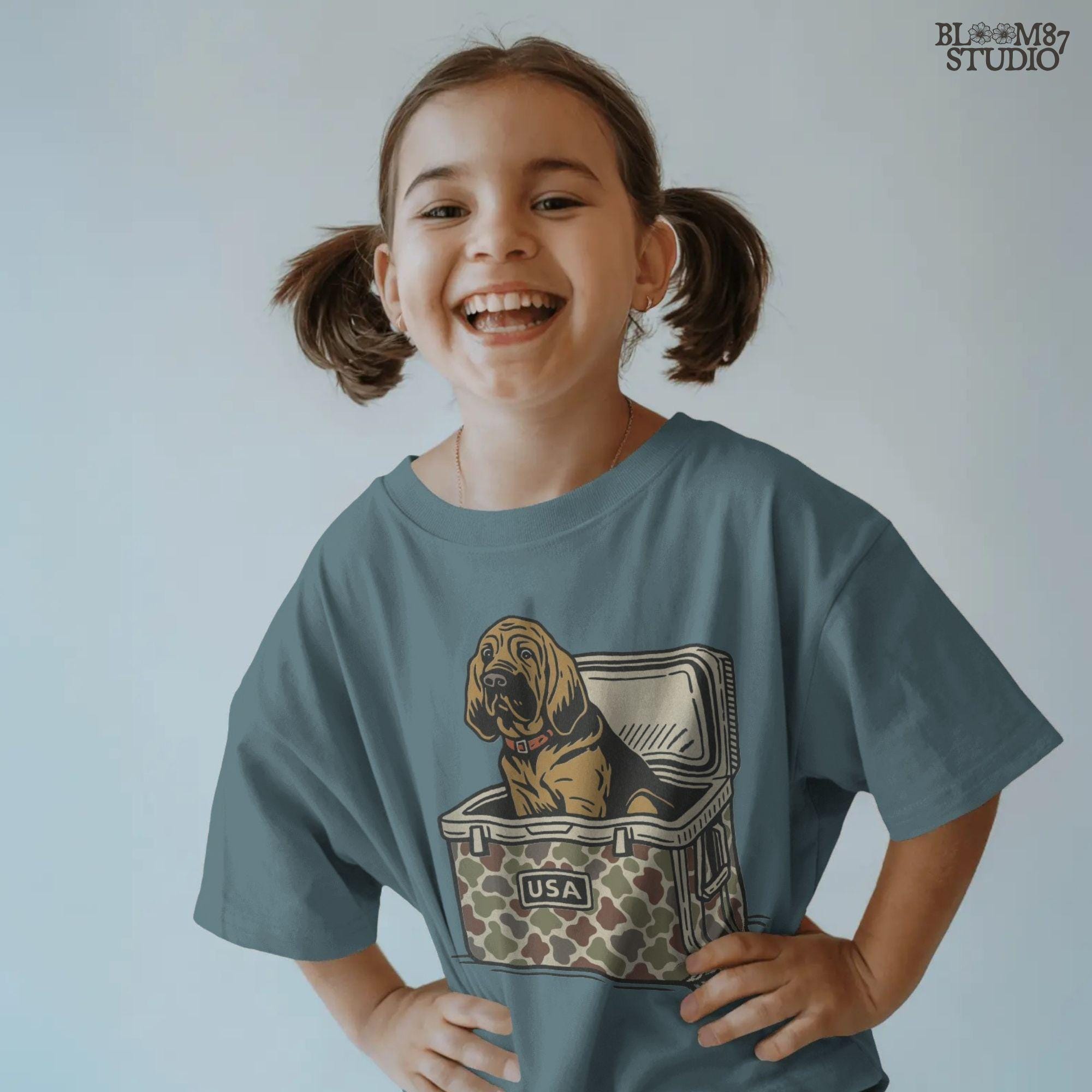 Illustration of a brown bloodhound dog sitting inside a camouflage cooler with “USA” label, hunting and outdoor-themed sublimation PNG design