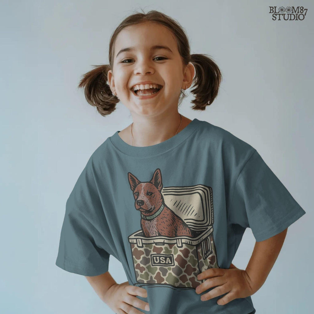 Illustration of an Australian Cattle Dog (Blue Heeler) sitting inside a camouflage cooler with “USA” label, rustic country-style sublimation PNG design