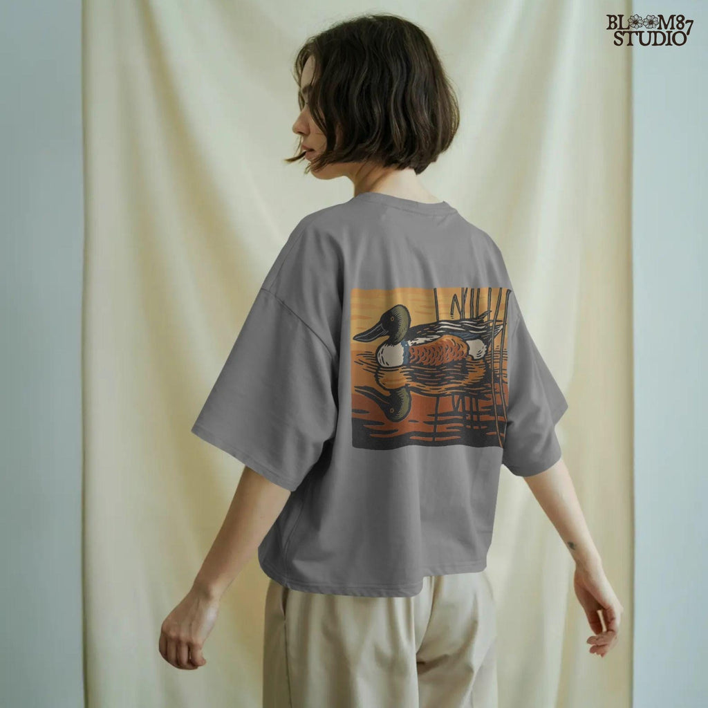 Illustration of a Northern Shoveler duck swimming in a marsh pond at sunset with warm orange and brown reflections, digital PNG for sublimation crafts