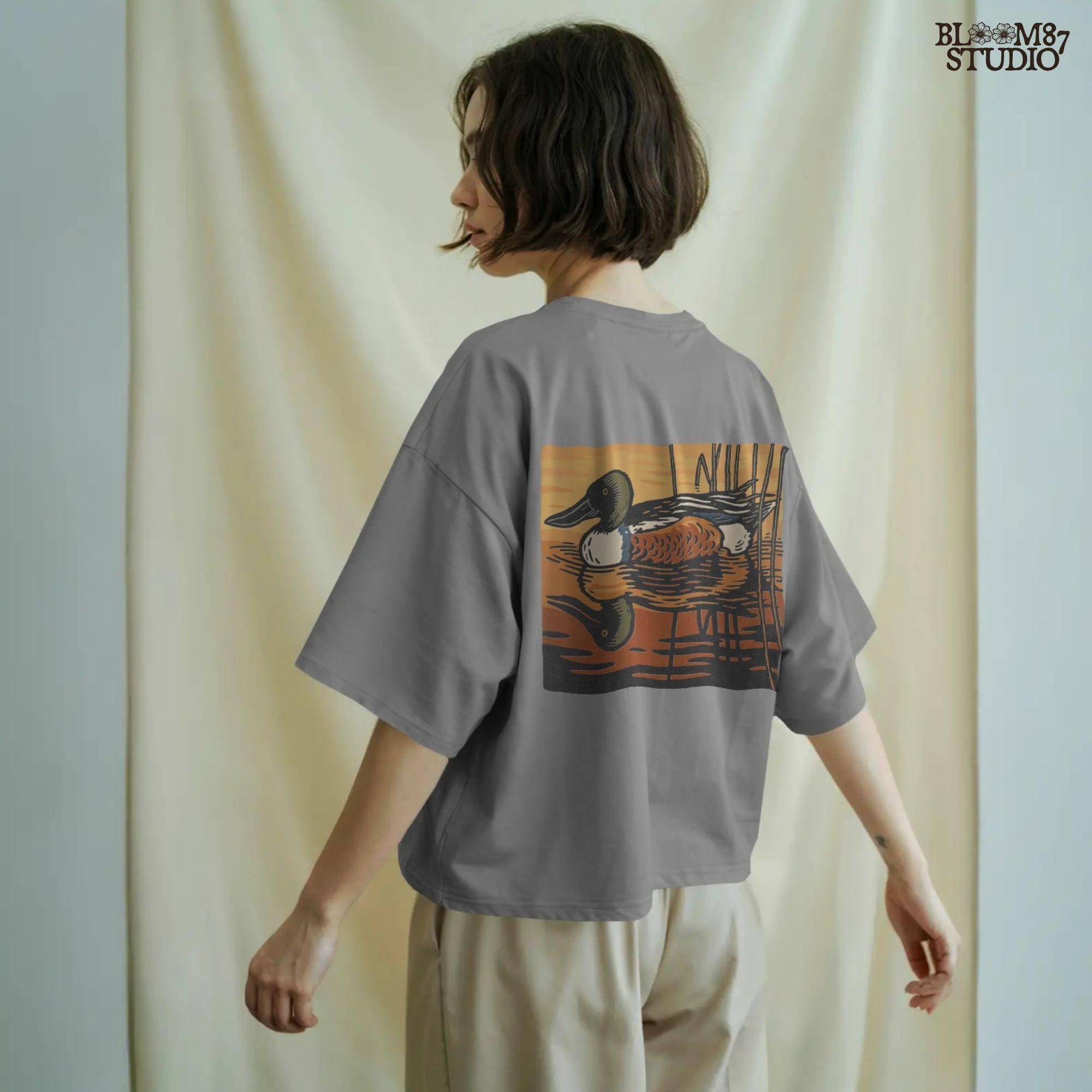 Illustration of a Northern Shoveler duck swimming in a marsh pond at sunset with warm orange and brown reflections, digital PNG for sublimation crafts