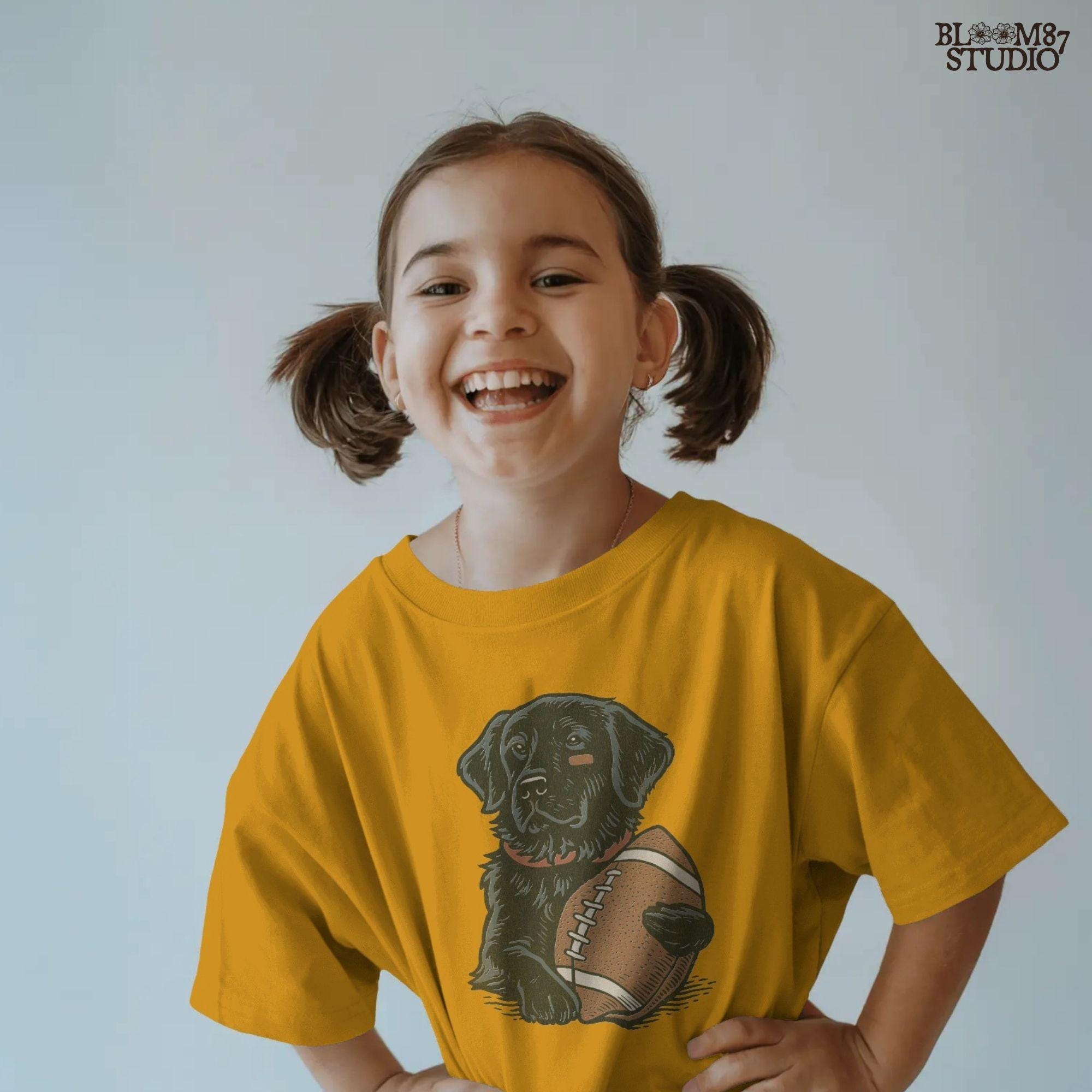 Illustration of a black Labrador Retriever holding a football, sublimation PNG design for game day and sports fan apparel.