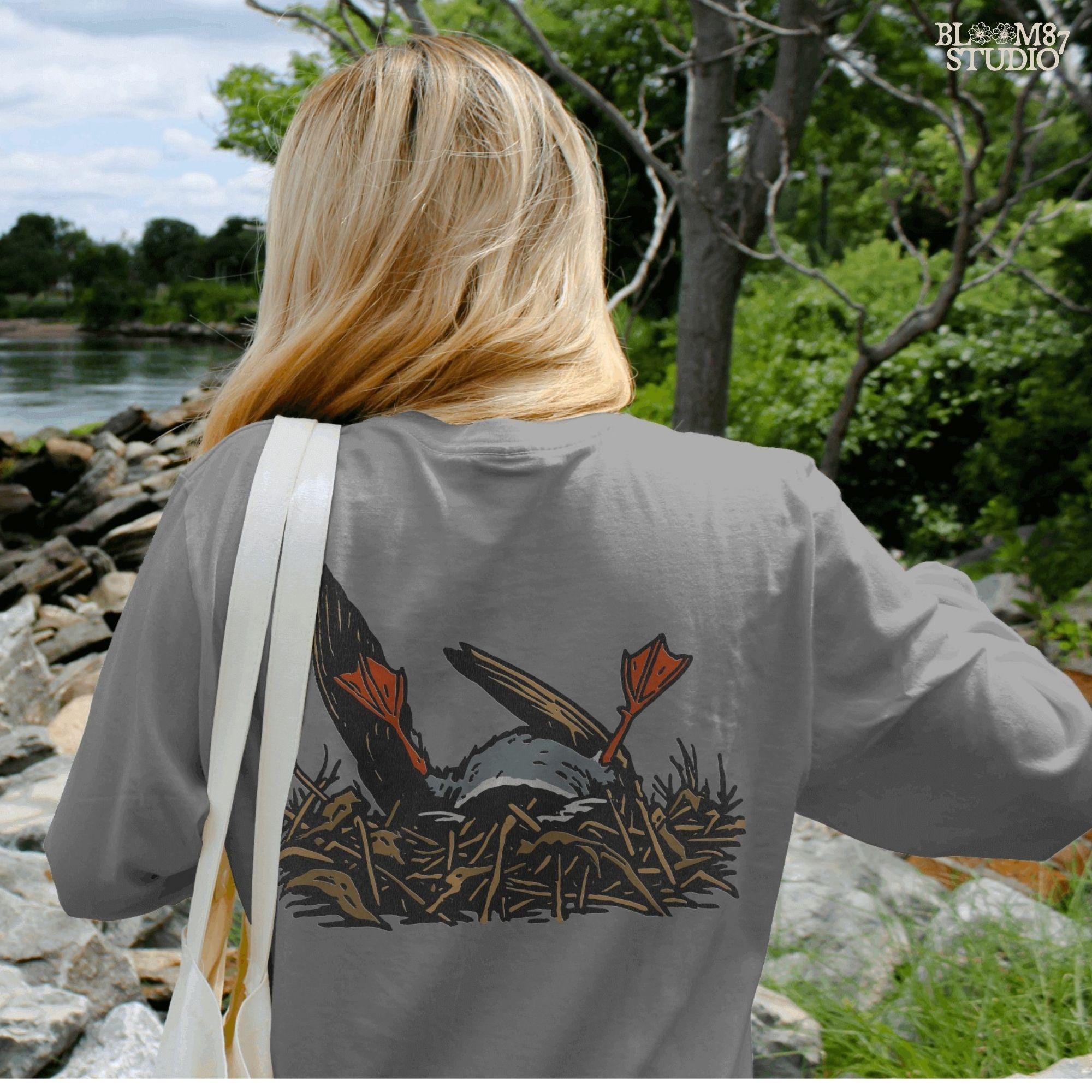 Solid Version:
Cartoon dead duck with orange feet lying in a nest, vintage style sublimation PNG for dark humor Halloween crafts.

Distressed Version:
Distressed-style dead duck illustration in a nest with exaggerated orange feet, ideal for rustic or spooky sublimation designs.