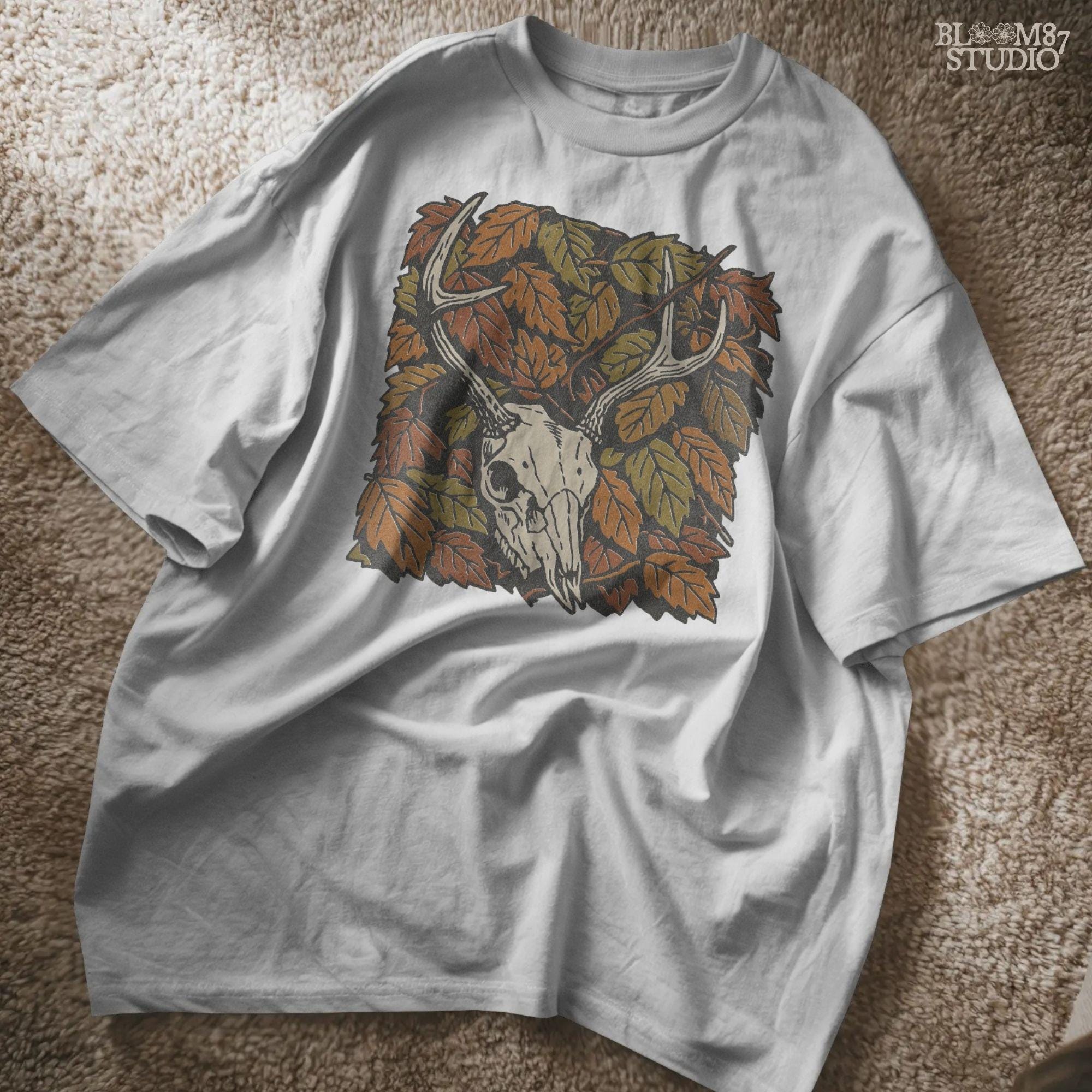 Deer skull with antlers surrounded by autumn leaves, rustic fall hunting sublimation PNG design.