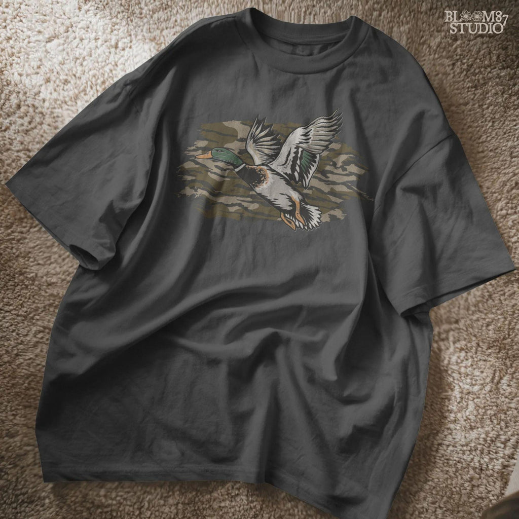 Solid version: Illustration of a flying mallard duck with green head and camouflage background, hunting sublimation PNG.
Distressed version: Vintage distressed flying mallard with camo background, rustic hunting sublimation PNG.