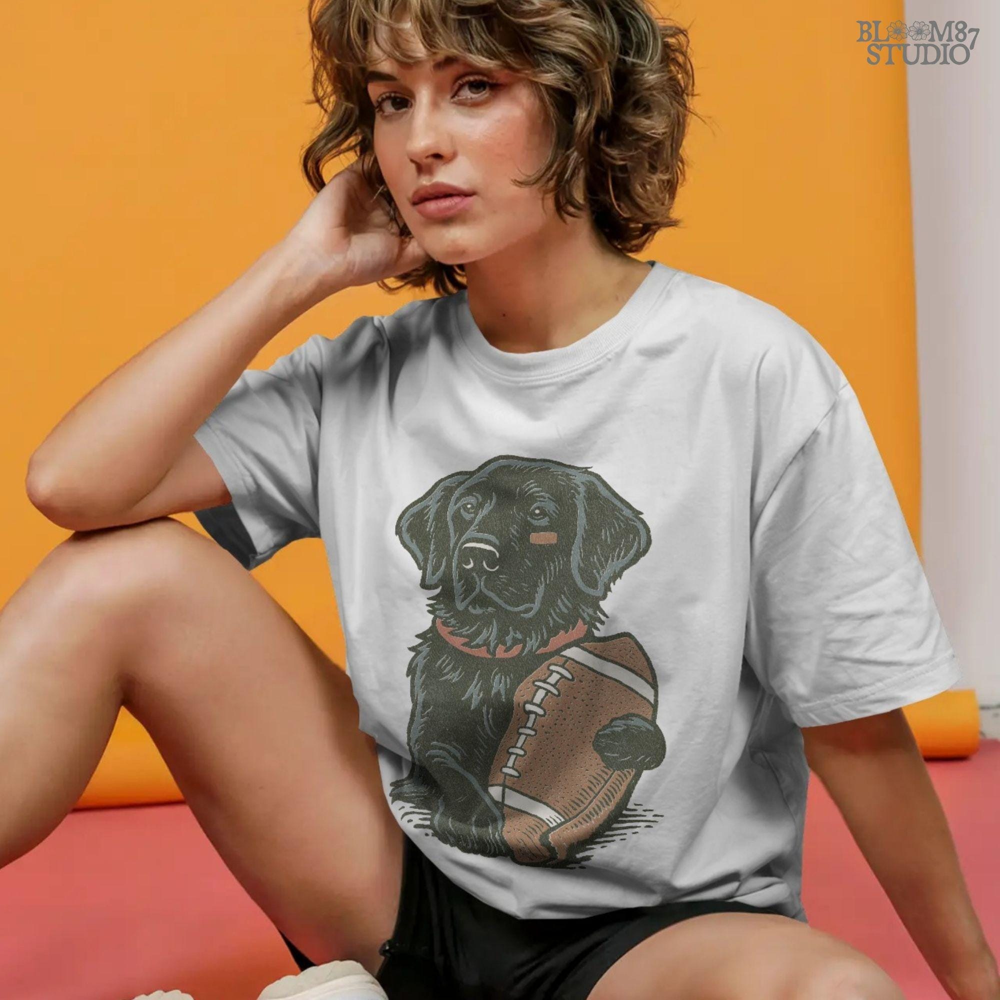 Illustration of a black Labrador Retriever holding a football, sublimation PNG design for game day and sports fan apparel.