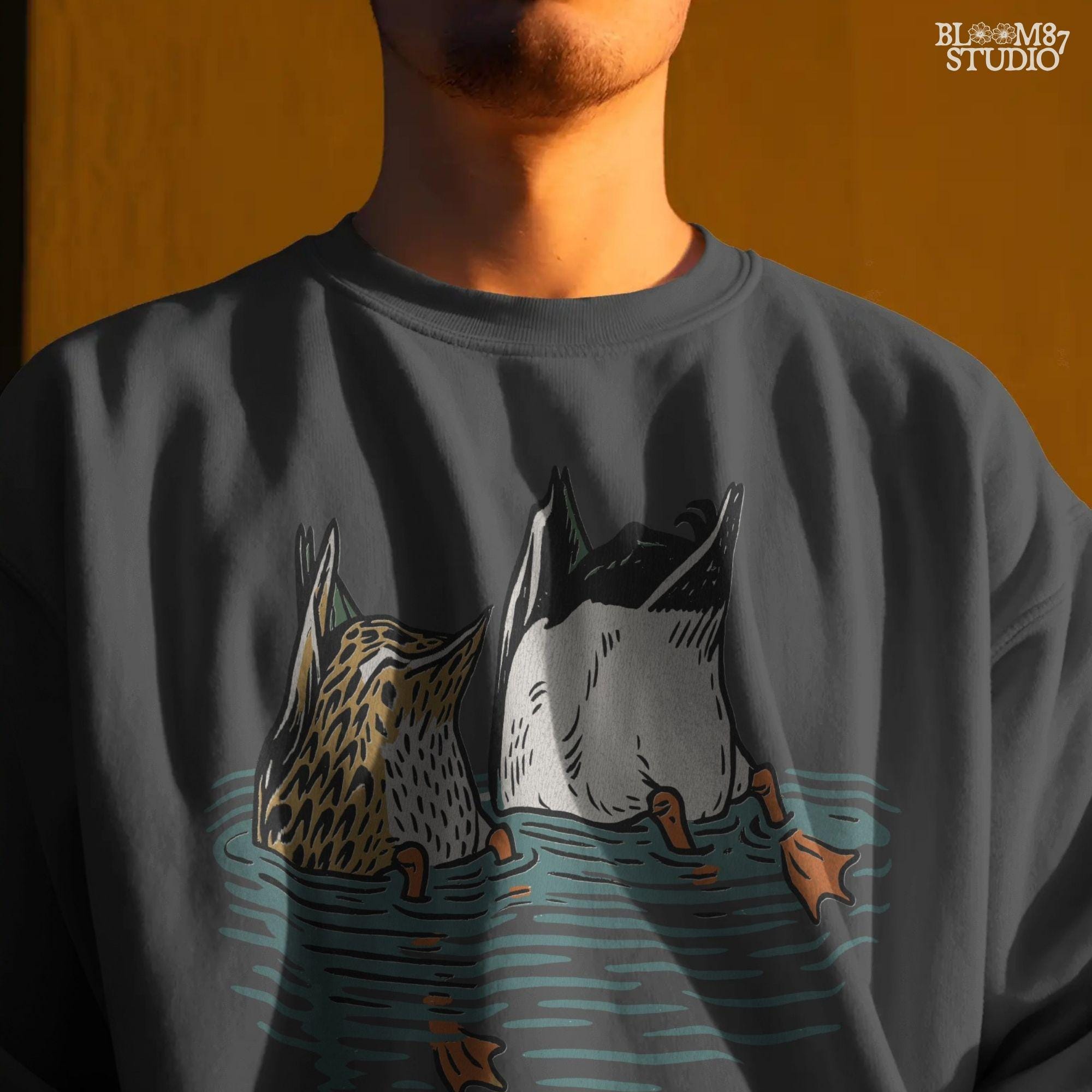 Solid version:
“Two ducks dabbling with tails up and feet in water – funny duck sublimation PNG for hunting shirts and rustic crafts”

Distressed version:
“Vintage distressed sublimation PNG of two ducks with tails up in pond – funny waterfowl hunting and rustic outdoor design”