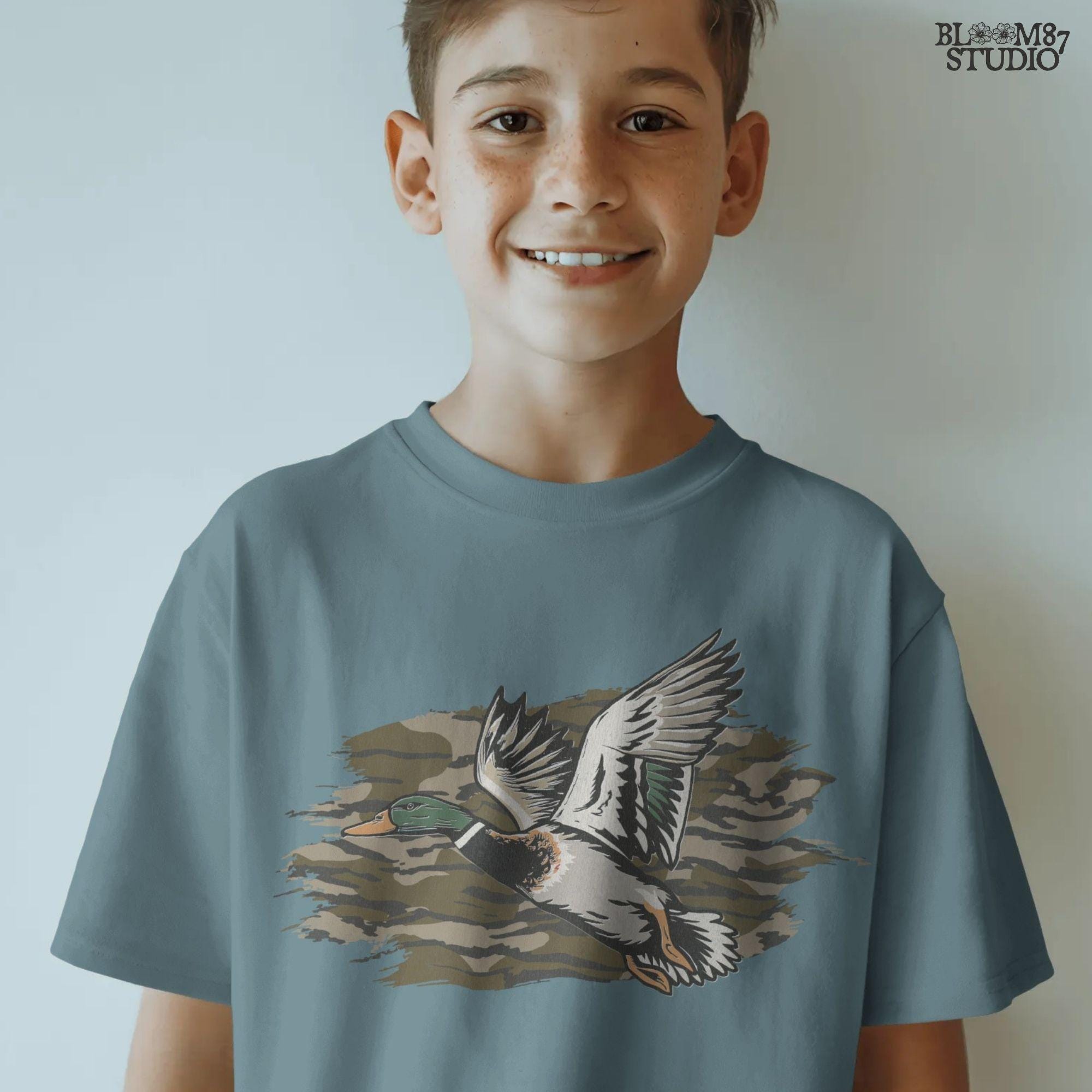 Solid version: Illustration of a flying mallard duck with green head and camouflage background, hunting sublimation PNG.
Distressed version: Vintage distressed flying mallard with camo background, rustic hunting sublimation PNG.