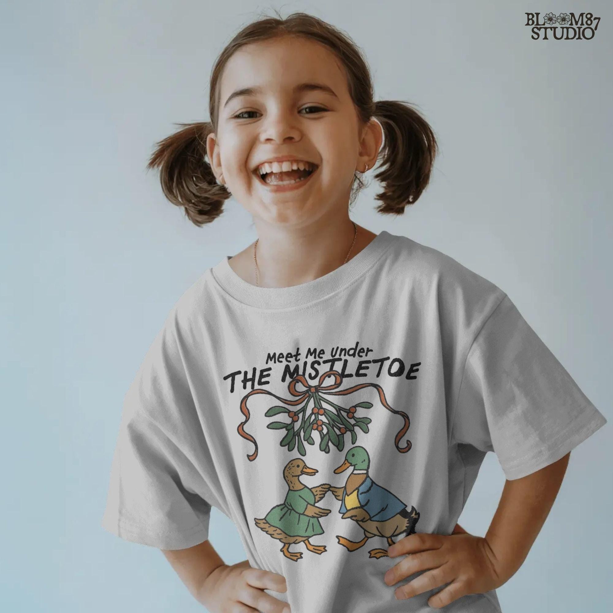 Seasonal animal graphic showing a male and female duck in cute clothes with a festive plant above them.